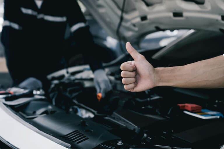 Thumbs up as an expert car mechanic performs a safety inspection to provide a road safety certificate.